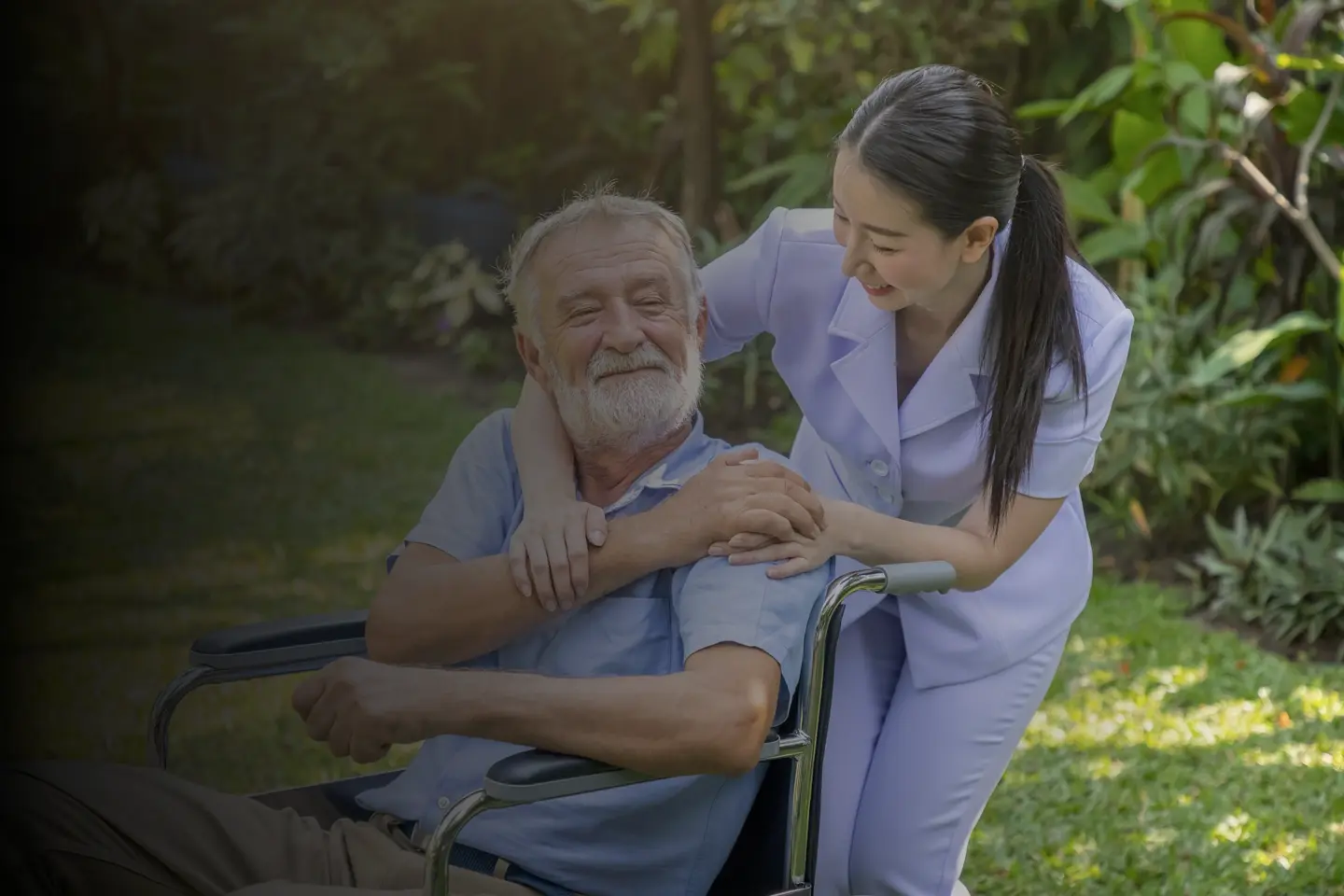 friendly nurse holding elderly mans hand in a wheelchair